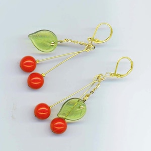 May include: A pair of dangle earrings with a green leaf charm and three red cherry-shaped beads on each earring.