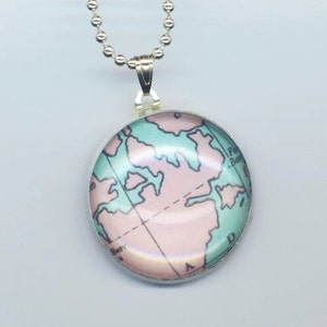May include: A silver chain necklace with a round glass pendant featuring a vintage map of the world in pink and blue tones.