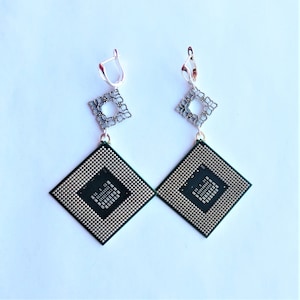 May include: A pair of silver earrings with a delicate floral design and a square-shaped computer chip pendant.