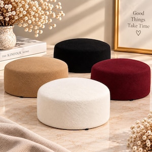 May include: Four round, low-profile ottomans with a textured, felt-like fabric finish. The set includes one white, one black, one tan, and one deep burgundy ottoman, each featuring a flat top surface and a simple, cylindrical shape.