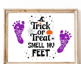 May include: A framed Halloween-themed print with the text "Trick or Treat Smell My Feet." The design includes purple footprints, a witch's hat, a spider web, an orange pumpkin, and stars. The frame is a light brown color.