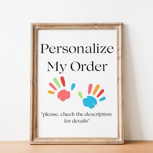 Könnte beinhalten: Ein weißes Schild mit dem Text "Personalisieren Sie meine Bestellung" in schwarzer Schrift. Unter dem Text befinden sich zwei bunte Handabdrücke. Der Text "*Bitte überprüfen Sie die Beschreibung für Details*" befindet sich am unteren Rand des Schildes.