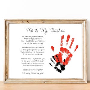 May include: Framed print with the text "Me & My Teacher" and a poem. The print features red and black handprints. The frame is a light brown color. The print is a sentimental gift for a teacher.