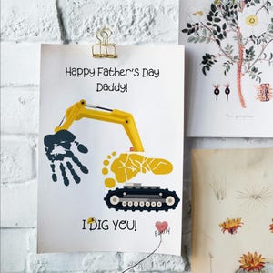May include: A white Father's Day card with the text "Happy Father's Day Daddy!" and a yellow excavator design made from a handprint and footprint. The card also says "I DIG YOU!" and has a heart with a name.