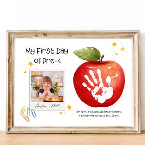 Pode incluir: Impressão emoldurada com o texto "My First Day of Pre-K" e uma foto de uma criança. Apresenta uma grande maçã vermelha com uma impressão de mão branca. A impressão inclui o texto "Austin, 2025" e uma citação.