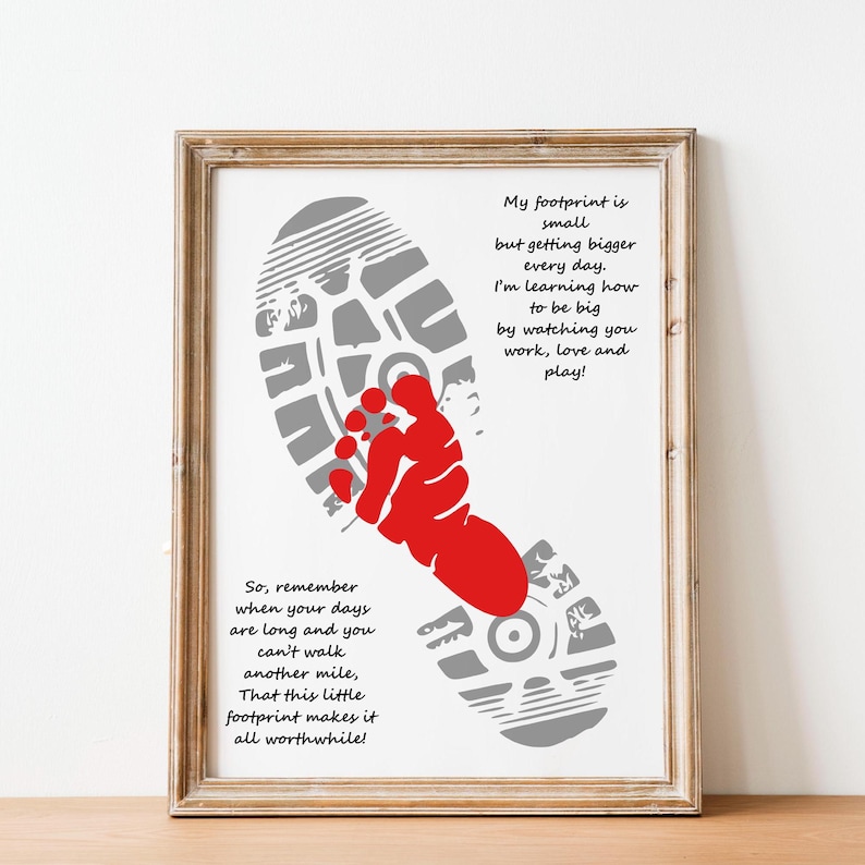 Op de afbeelding: Ingelijste print met een grijze voetafdruk en een rode handafdruk. De print bevat inspirerende tekst in het zwart, tegen een witte achtergrond. De lijst is lichtbruin.