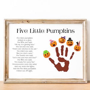 May include: A framed print featuring the text "Five Little Pumpkins" and a poem about pumpkins. The artwork includes five cartoon pumpkins with different hats and a brown handprint. The frame is a light brown color.