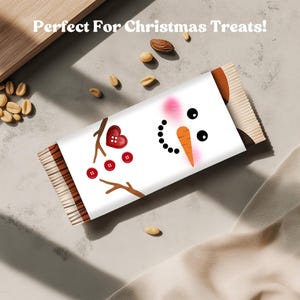 May include: A white candy bar wrapper with a snowman design. The snowman has a carrot nose, black eyes, and a mouth made of black dots. The wrapper also features a heart and red buttons. The text "Perfect For Christmas Treats!" is at the top.