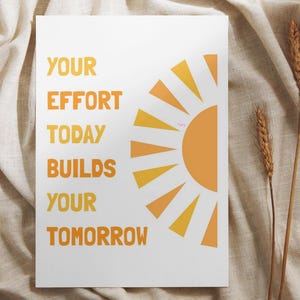 May include: A white poster with the text "YOUR EFFORT TODAY BUILDS YOUR TOMORROW" in orange. A stylized orange and yellow sun graphic is on the right. Two stalks of wheat are on the right side of the poster.