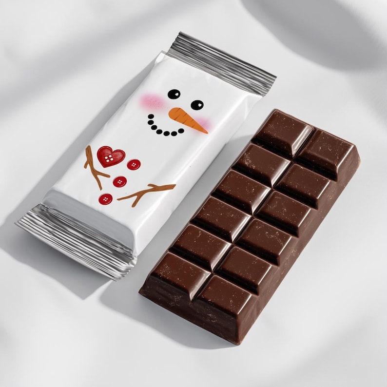 May include: A dark chocolate bar next to a wrapped chocolate bar. The wrapped bar has a snowman face design with a carrot nose, black eyes, and a smiling mouth. The snowman has a red heart and buttons.