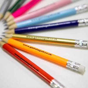 May include: A collection of colorful pencils, including red, orange, gold, blue, and pink, with white erasers. The pencils have the website address www.gamolagolf.co.uk printed on them. The pencils are arranged in a fan shape.