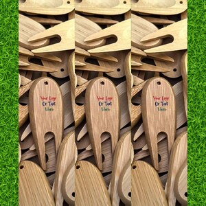 May include: A close-up of three wooden golf ball retrievers with a fork-like design. The retrievers are surrounded by other wooden golf ball retrievers. The retrievers have a blank space for a logo or text that reads "Your Logo Or Text Here".