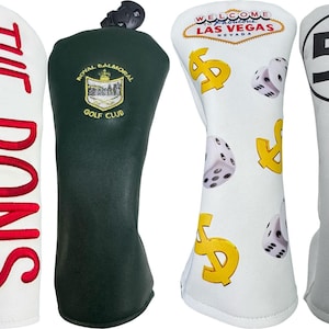 Könnte beinhalten: Vier Golfschlägerhauben. Die erste ist weiß mit rotem Schriftzug THE DONS. Die zweite ist dunkelgrün mit dem Logo des Royal Balmoral Golf Club. Die dritte ist weiß mit gelben Dollarzeichen und Würfeln. Die vierte ist weiß mit einem roten und blauen Streifen sowie der Zahl 53.