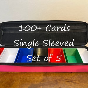 May include: Pink carrying case with five compartments for storing cards. The case is open and shows five compartments, each with a different color: red, white, blue, black, and green. The case is labeled "100+ Cards Single Sleeved Set of 5".