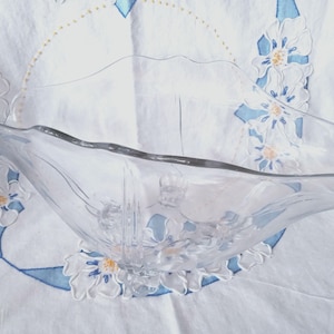 May include: A clear glass serving bowl with a scalloped edge and a floral design. The bowl is made of clear glass and has a delicate, feminine look.