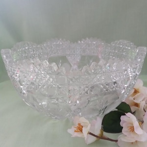 May include: A large, clear glass bowl with a cut glass design. The bowl has a scalloped edge and a wide, round base.