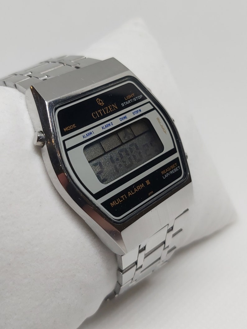 May include: A silver Citizen Multi Alarm II digital watch with a black face and a silver metal strap. The watch has a range of functions, including alarm, stopwatch, and timer.