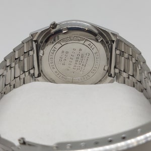 May include: A silver Citizen watch with a stainless steel band. The back of the watch has the text "Citizen Watch Co. 4-058463 Y 0022361 GM-4-5 40-3011 14 Water Resistant All Stainless Steel Japan" engraved on it.