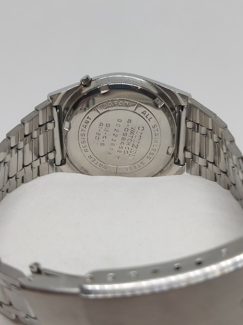May include: A silver Citizen watch with a stainless steel band. The back of the watch has the text "Citizen Watch Co. 4-058463 Y 0022361 GM-4-5 40-3011 14 Water Resistant All Stainless Steel Japan" engraved on it.
