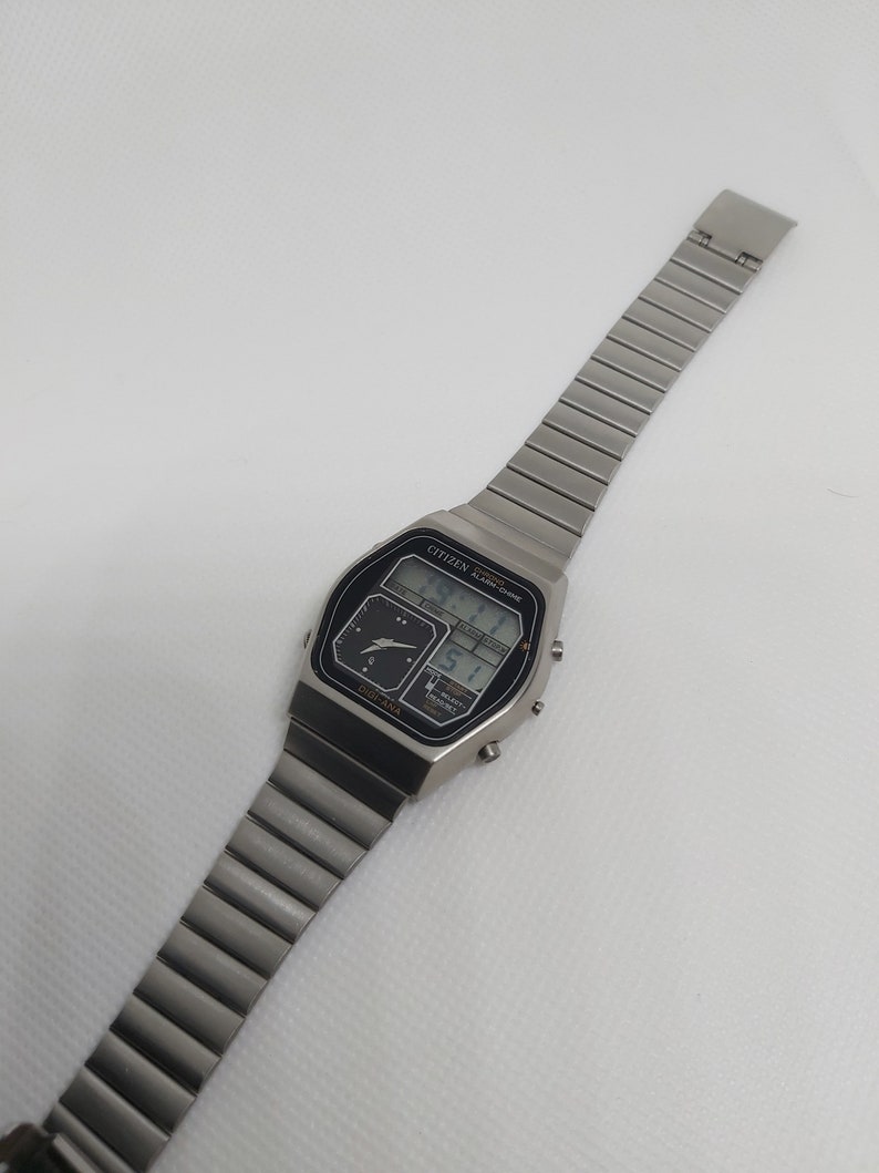May include: A silver Citizen analog-digital watch with a black face and a silver metal band. The watch face displays the time, date, and day of the week.