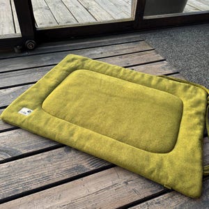 May include: A green rectangular pet bed with a raised edge and a sewn-in label that says "Pet Life".