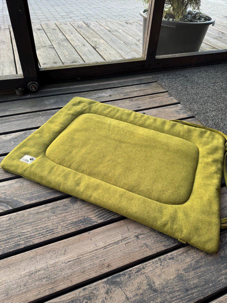 May include: A green rectangular pet bed with a raised edge and a sewn-in label that says "Pet Life".