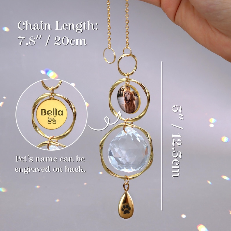 May include: A gold-colored pet memorial suncatcher with a photo and the name "Bella". The suncatcher has a clear crystal ball and a paw print charm. Chain length is 7.8 inches (20cm), and the total length is 5 inches (12.5cm).