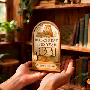 May include: Wooden book counter with an owl illustration reading a book, and the text "BOOKS READ THIS YEAR". The counter displays the number 123. The base reads "Christy's Library".