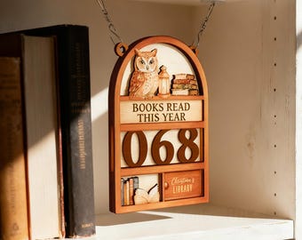 May include: Wooden bookshelf-shaped sign featuring an owl, lantern, and books. The sign reads "BOOKS READ THIS YEAR" and displays the number "068". The bottom section says "Christina's Library".
