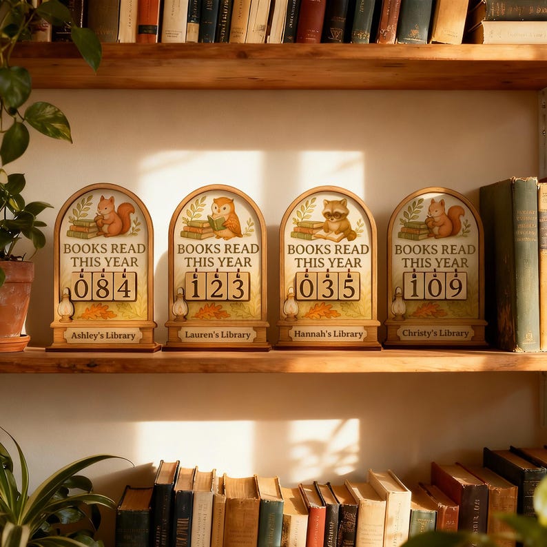 May include: Wooden book counter with the text "BOOKS READ THIS YEAR" and a number display. Each counter features a different woodland animal: a squirrel, an owl, a raccoon, and another squirrel. The counters are on a wooden shelf.