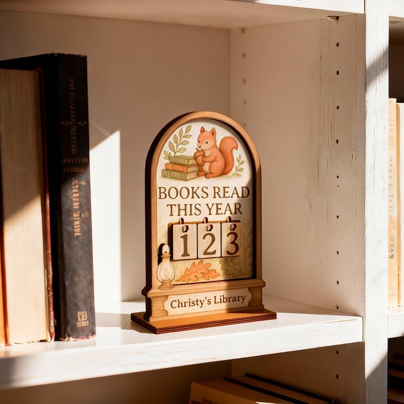May include: Wooden bookshelf decor with a squirrel illustration above the text "BOOKS READ THIS YEAR". The counter reads "123". The base reads "Christy's Library". The decor is on a white shelf with books on either side.