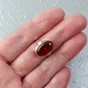 Puede incluir: Un anillo de plata con una piedra de &aacute;mbar ovalada grande.