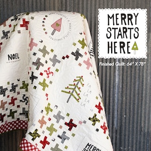 May include: A white quilt with a red and white gingham border. The quilt features a patchwork design with various green, red, and black squares and crosses. The quilt is decorated with the text "Merry Starts Here" and a small Christmas tree. The quilt is 64 inches by 78 inches.