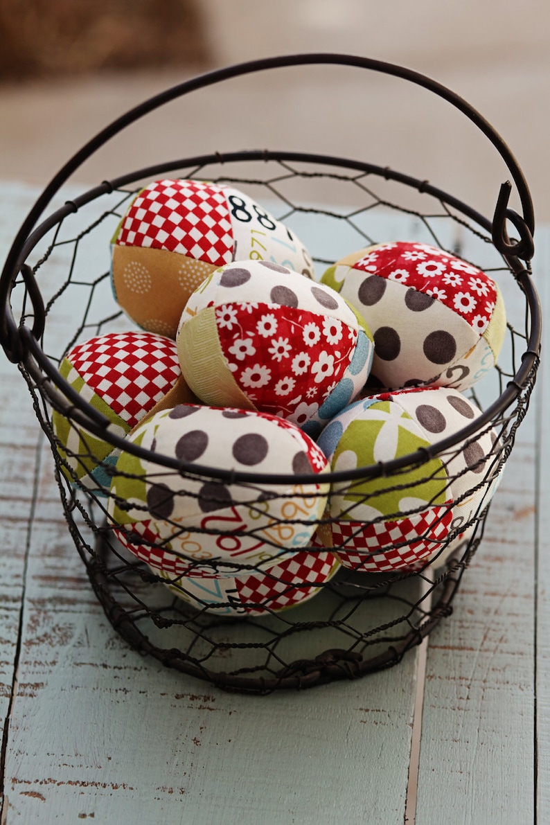 May include: A wire basket filled with colorful fabric balls. The balls are made of patchwork fabric with different patterns, including polka dots, checkered, and floral designs.