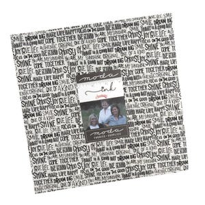 Könnte beinhalten: Ein quadratischer Stapel aus Stoffquadraten mit einem schwarz-weißen, sich wiederholenden Muster aus inspirierenden Phrasen wie "Dream Big", "Be Kind" und "Shine". Ein zentrales Papierband zeigt den Text "moda ink" und ein Foto von drei Personen.