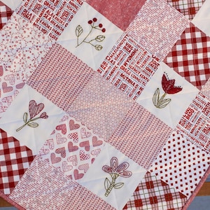 May include: A red and white patchwork quilt with a variety of patterns, including gingham, hearts, and floral designs. The quilt is made with a white background and red accents. The quilt is made with a variety of fabrics, including cotton and linen. The quilt is a great way to add a touch of warmth and style to any room.