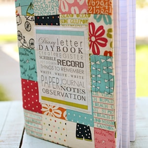 May include: A colorful fabric-covered notebook with a patchwork design. The cover features a variety of patterns, including polka dots, flowers, and geometric shapes. The notebook has a title label that reads "Diary letter DAYBOOK createREGISTER SCRIBBLE RECORD JOT DOWN THINGS TO REMEMBER WRITE.WRITE.WRITE PAPER JOURNAL NOTES OBSERVATION".