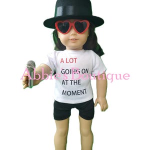 Custom shirt, shorts, glasses, black hat, and shoes all designed to fit 18-inch dolls. This adorable outfit is inspired by the Eras Tour.