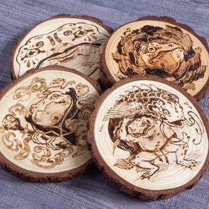 Può includere: Quattro sottobicchieri in legno con intricati disegni pirografati di creature mitiche. Ogni sottobicchiere è una fetta circolare di legno con un bordo di corteccia naturale. L'opera d'arte è dettagliata e presenta una calda tonalità marrone.