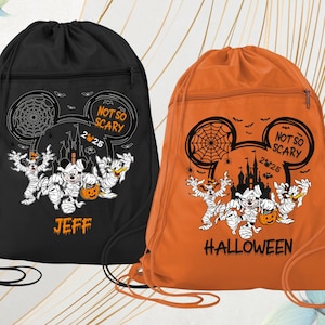 May include: Two drawstring bags, one black and one orange, featuring a Halloween-themed design. The design includes a spiderweb, Mickey Mouse ears, and cartoon characters dressed as mummies. The black bag says "JEFF" and the orange bag says "HALLOWEEN".