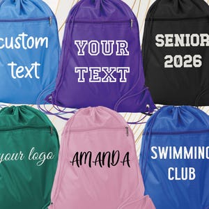 May include: A collection of drawstring backpacks in various colors: blue, purple, black, green, and pink. Each bag features a zippered pocket and personalized text, including "custom text," "your text," "Senior 2026," "your logo," "Amanda," and "Swimming Club."
