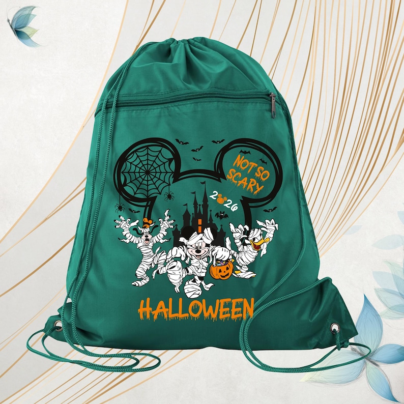 May include: A dark green drawstring backpack featuring a graphic of cartoon characters dressed as mummies. The design includes a castle silhouette, spiderwebs, bats, and the text "NOT SO SCARY 2024 HALLOWEEN" printed in orange and white.