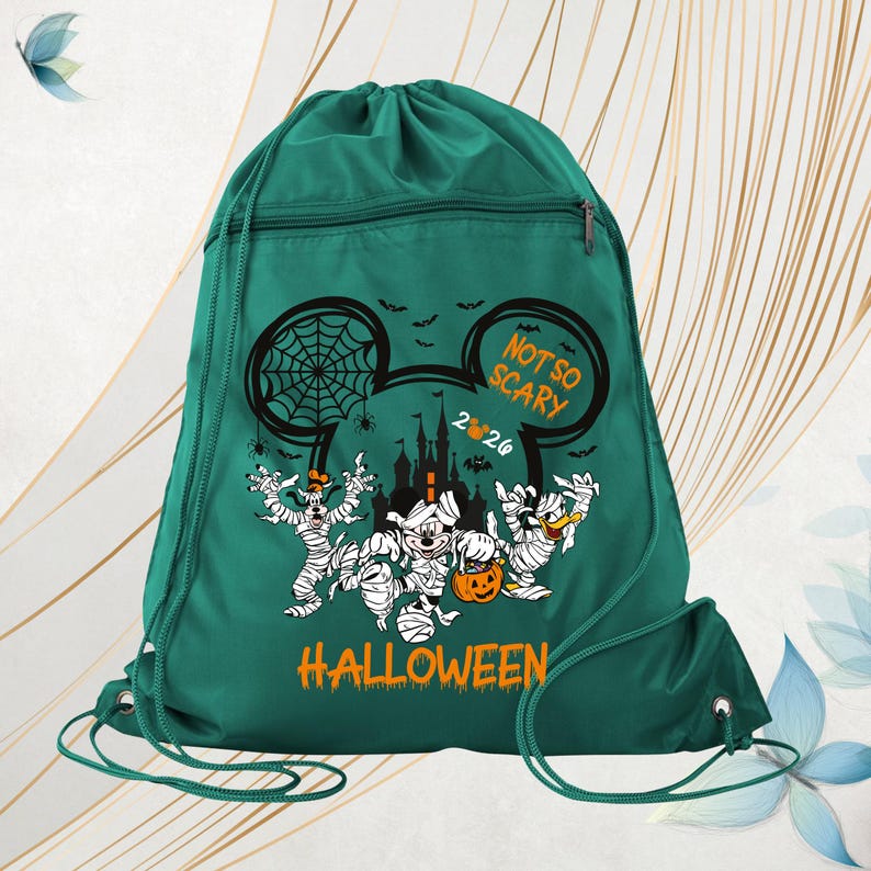 May include: A dark green drawstring backpack featuring a graphic of cartoon characters dressed as mummies. The design includes a castle silhouette, spiderwebs, bats, and the text "NOT SO SCARY 2024 HALLOWEEN" printed in orange and white.