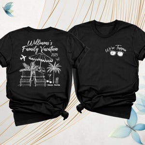 Pode incluir: Duas camisetas pretas. Uma apresenta o texto "Williams's Family Vacation 2025" com gr&aacute;ficos tem&aacute;ticos de praia. A outra camisa tem o texto "We're Trippin" com &oacute;culos de sol. Ambas as camisas t&ecirc;m mangas curtas e gola redonda.