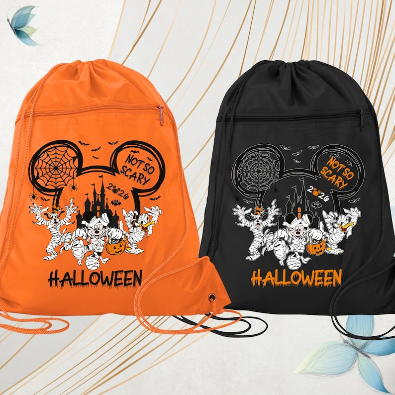 May include: Two drawstring backpacks, one orange and one black, featuring a graphic of Mickey Mouse ears with a spiderweb, a castle, and characters wrapped like mummies. The design includes the text NOT SO SCARY 2026 and HALLOWEEN.
