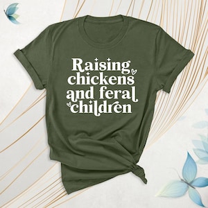 Peut inclure: Un t-shirt vert avec le texte "Raising chickens and feral children" en lettres blanches.