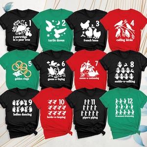 May include: A collection of twelve t-shirts in black, red, and green, each featuring a white graphic representing a day from the Twelve Days of Christmas, including numbered labels from 1 to 12 and corresponding text descriptions.