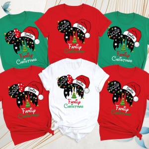 May include: A collection of red, green, and white t-shirts featuring a graphic of Mickey Mouse ears with a Santa hat, a Christmas tree, string lights, and snowflakes. The text reads 2026, Smith, and Family Christmas in various colors.