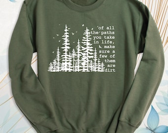 May include: An olive green crewneck sweatshirt featuring a white graphic print of a forest silhouette with birds and the text: of all the paths you take in life, make sure a few of them are dirt. The garment has long sleeves and ribbed cuffs.