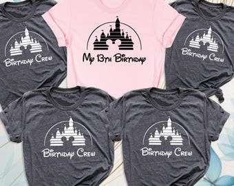 May include: A light pink t-shirt with black text reading My 13th Birthday and a castle graphic, surrounded by four dark gray t-shirts with white text reading Birthday Crew and a castle graphic, all featuring a circular arch design.
